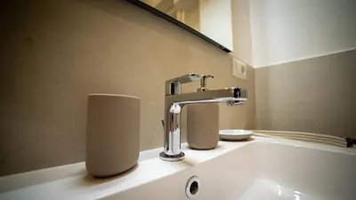 a bathroom sink with a faucet and two rolls of toilet paper at Bliss House near Vatican City in Rome
