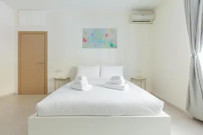 a white bedroom with a white bed with towels on it at Hostly-The Happya Charme Suite in Rome