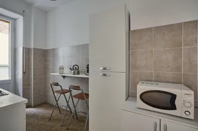 a kitchen with a microwave and a counter with stools at Domus Erasmo in Rome