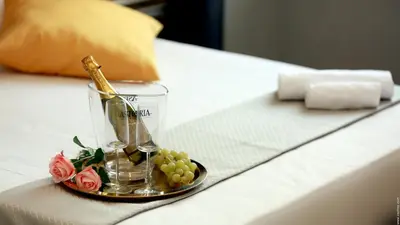 a glass vase with flowers and grapes on a bed at Hotel Giolitti Smart in Rome