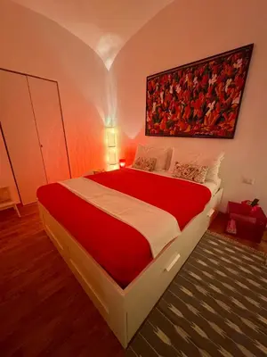 a bedroom with a large red bed with a painting on the wall at Ao Apartment in Rome