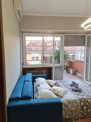 a bedroom with a blue couch and a large window at La Terrazza su Roma in Rome