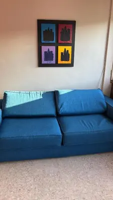 a blue couch in a room with paintings on the wall at La Terrazza su Roma in Rome