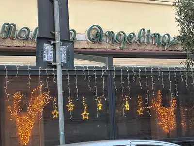 a street sign with christmas lights on the side of a building at La Terrazza su Roma in Rome