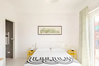 a white bedroom with a bed and a window at Sunset House - San Paolo in Rome