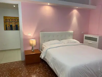 a bedroom with a white bed with a pink wall at Dimora Davide in Rome