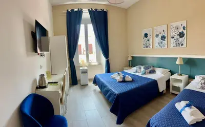 a hotel room with two beds and a chair at Girasole Guesthouse in Rome