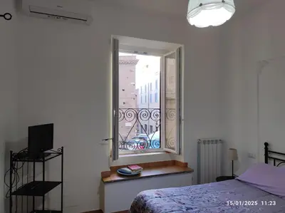 a bedroom with a bed and a window with a balcony at Il Grillo ai Fori Romani in Rome