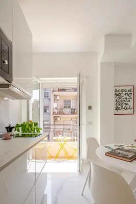 a white kitchen with a table and chairs at Sunrise House - San Paolo in Rome