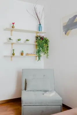 a chair in a living room with plants on shelves at Casa Buonarroti, Rome, City Center, Elegant and Quiet Apartment in Rome