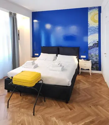 a bedroom with a large bed with a yellow suitcase on it at Prisma Rooms in Rome