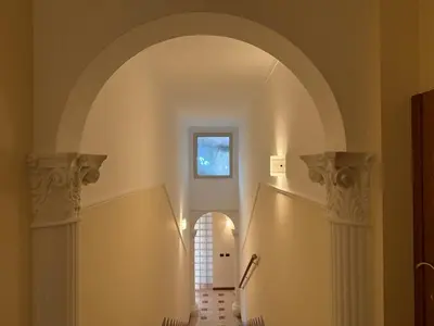 a hallway with an archway and stairs with a window at Apartment in the heart of EUR in Rome