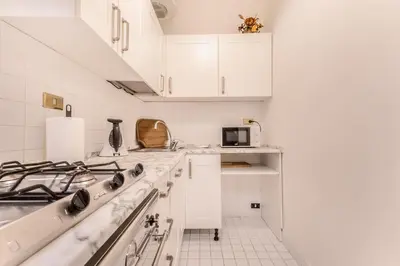 a white kitchen with white cabinets and a stove at Casa Iside in Rome