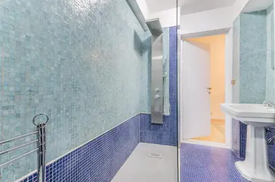 a blue tiled bathroom with a shower and a sink at Casa Iside in Rome