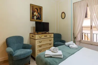 a bedroom with a bed and a chair and a television at GuestHost - Piazza Navona Elegant Apartment in Rome