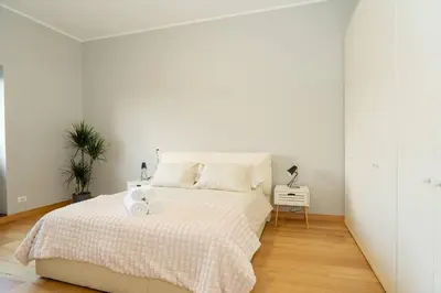 a white bedroom with a white bed and a plant at Divine View Apartment in Rome