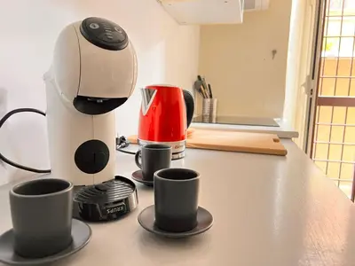a coffee maker and three cups on a counter at La casa di Nina in Rome