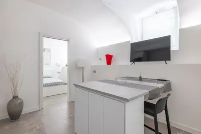 a white kitchen with a bar with a tv on the wall at Cecilia Guest House in Rome
