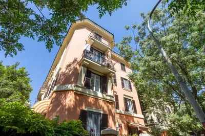 a building with a balcony in the middle of trees at Cecilia Guest House in Rome