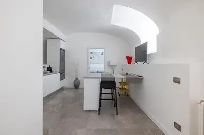 a kitchen with white walls and a table with a stool at Cecilia Guest House in Rome