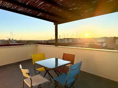 a table and chairs on a balcony with the sunset at Marconi Penthouse in Rome