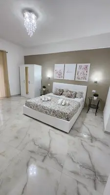 a white bedroom with a large bed with marble floors at L'impero dei fiori in Rome
