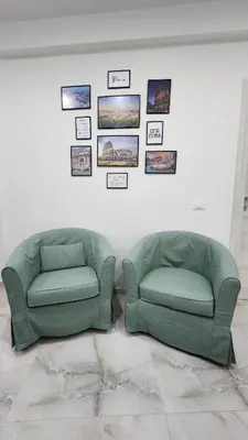 two green chairs in a room with pictures on the wall at L'impero dei fiori in Rome