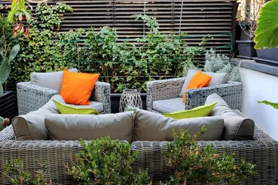 a patio with wicker chairs with orange and green pillows at Vico Rooms and Terrace in Rome