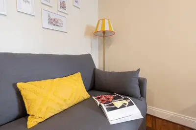 a gray couch with a yellow pillow and a book at Coppelle Charme in Rome