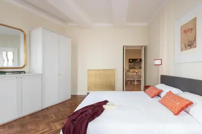a white bedroom with a large white bed with orange pillows at Coppelle Charme in Rome