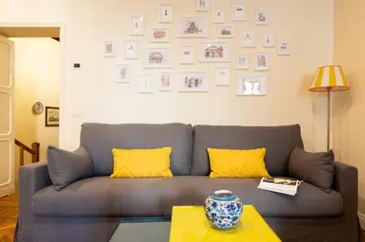 a living room with a gray couch and pictures on the wall at Coppelle Charme in Rome