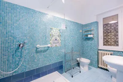 a blue tiled bathroom with a shower and a toilet at Casa Emiliani Ospedale San Camillo - Cale 09 in Rome