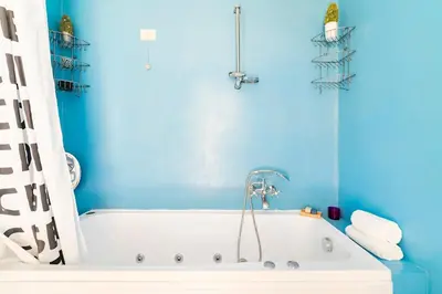 a blue bathroom with a white tub and a blue wall at Principe House, Central Rome, 3 bedroom 2 bath, Elegant Apartment full of Light in Rome