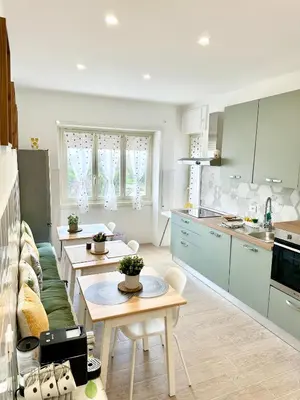 a kitchen and living room with tables and a couch at Monti Tiburtini Roma Guest House Apartment in Rome