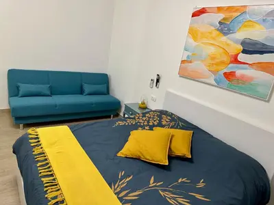 a bedroom with a bed with a yellow blanket and a couch at Monti Tiburtini Roma Guest House Apartment in Rome