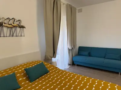 a bedroom with a bed and a blue couch at Monti Tiburtini Roma Guest House Apartment in Rome