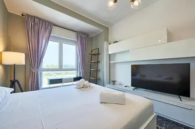 a bedroom with a large white bed with a flat screen tv at Modern Comfort Steps from Tiburtina Station in Rome