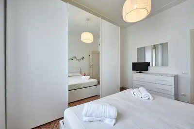 a white bedroom with a bed and a mirror at Modern Comfort Steps from Tiburtina Station in Rome