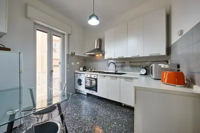 a kitchen with white cabinets and a glass table at Modern Comfort Steps from Tiburtina Station in Rome
