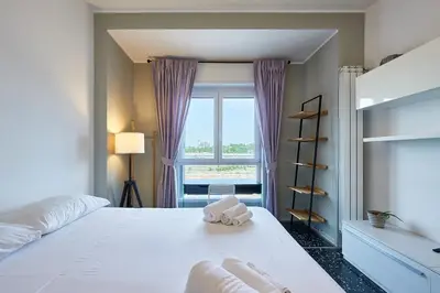 a bedroom with a large white bed and a window at Modern Comfort Steps from Tiburtina Station in Rome