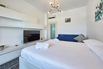 a white bedroom with a large bed and a tv at Modern Comfort Steps from Tiburtina Station in Rome