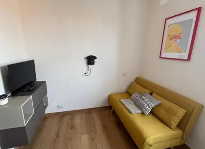 a living room with a yellow couch and a television at Duck House Gemelli in Rome
