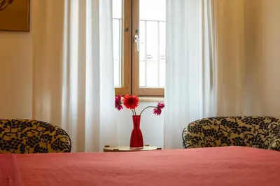 two chairs and a red vase with flowers in a window at kis inn affitacamere guesthouse in Rome