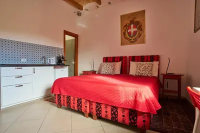 a bedroom with a red bed and a kitchen at kis inn affitacamere guesthouse in Rome