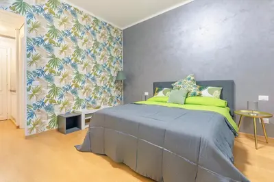a bedroom with a bed with green sheets and a wall at Renè home - Ponte Milvio in Rome