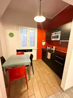 a kitchen with a table and chairs and a kitchen with red walls at Lovely flat next to vatican - private entrance in Rome