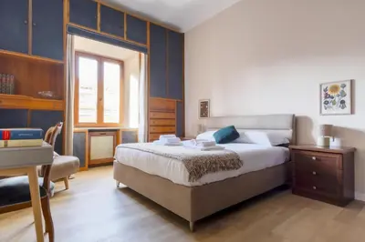 a bedroom with a large bed and a desk at Elegantis La ParioLina Apartment in Rome
