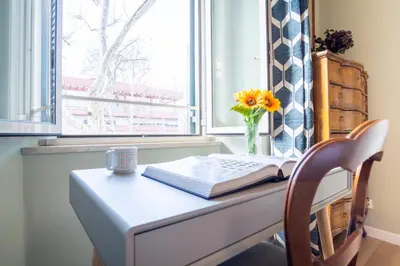a window with a desk with a book and a vase of flowers at Elegantis La ParioLina Apartment in Rome