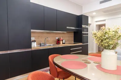 a kitchen with a table and chairs and a kitchen with black cabinets at MADI Collection Colosseum in Rome
