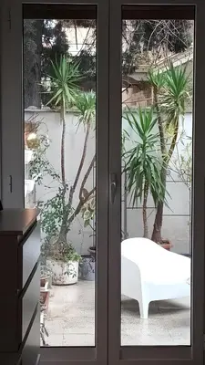 a sliding glass door with a white couch in front of palm trees at Casa verde di Mia in Rome